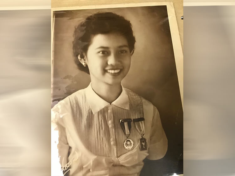 An elegant vintage black-and-white portrait captures a young Dr. Tupasi in a formal, short-sleeved button-down clinical shirt, smiling warmly with a commemorative medical medal pinned to her pocket.